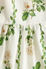 Vestido midi en popelina de algodón blanco con estampado floral y de enredaderas verdes, escote corazón, tirantes finos con lazo y falda con vuelo.