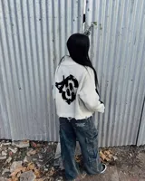 Sweater de punto color blanco con diseño gráfico negro en la espalda, cuello alto y detalles desgastados en los bordes.
