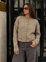 Cardigan negro de tejido de punto con cuello redondo, manga larga y cierre frontal de botones dorados metálicos grabados.
