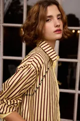 Camisa de algodón con diseño a rayas verticales en color amarillo y bordó. Presenta cuello clásico, cierre frontal con botones y un delicado detalle bordado de pequeñas flores a lo largo de la costura del canesú.
