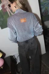 Campera tejida de punto con textura de rayas verticales, cierre frontal completo y cuello alto. Diseño de manga larga con hombros caídos.