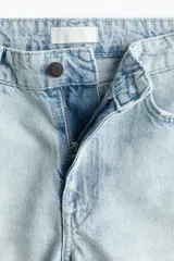 Bermuda de jean de cinco bolsillos en denim de algodón, de tiro medio y corte holgado con piernas amplias y terminación deshilachada.