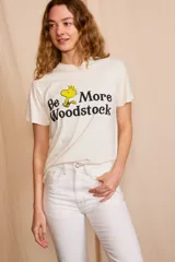 Remera color crema con estampado de Woodstock y la frase "Be More Woodstock".