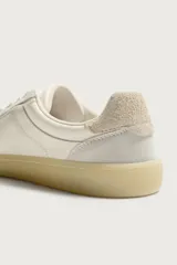 Zapatilla deportiva estilo barefoot fabricada en piel. Presenta un diseño de paneles combinados, puntera redondeada y ancha para mayor libertad de movimiento, plantilla OrthoLite extraíble y suela de goma fina en contraste.