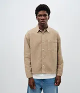 Camisa de sarga de algodón con acabado cationizado que le otorga un aspecto ligeramente desgastado. Presenta un corte boxy amplio, cuello clásico, cierre frontal con botones y un bolsillo aplicado en el pecho.