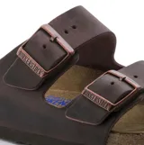 Sandalias Birkenstock modelo Arizona con diseño de dos correas ajustables. Confeccionadas en cuero nobuk aceitado, cuentan con plantilla anatómica Soft Footbed con capa de espuma adicional para mayor confort y suela resistente.