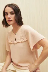 Blusa color durazno con textura sutil, detalle de encaje en el canesú y pequeño volado. Mangas cortas amplias y corte fluido.