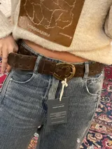 Cinto de cuero marrón con diseño trenzado y hebilla metálica en forma de herradura.