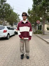 Buzo tipo polo de corte relajado y fit boxy, con diseño de bloques de color en bordó y blanco. Presenta cuello camisero con cierre frontal parcial y logo bordado en el pecho.