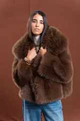 Tapado de piel sintética en color marrón chocolate, con diseño de corte amplio y largo a la cadera. Presenta un cuello envolvente de gran volumen y mangas largas, con interior forrado.