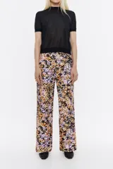 Pantalón de pana con estampado floral en tonos rosa, naranja y negro. Modelo de corte recto con largo tobillero, cierre con botón y cremallera frontal, bolsillos laterales en delantero y plastrón en la parte posterior.