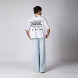 Remera gris oscuro de corte boxy, manga corta amplia, con cuello redondo y diseño gráfico frontal con la palabra "CONCEPTO" delineada en blanco dentro de un panel horizontal.