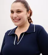 Suéter de punto en color bordó con corte slim, cuello polo y mangas largas. Presenta detalles de líneas blancas en contraste en el cuello y los puños, con acabado acanalado.