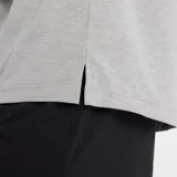 Remera de entrenamiento New Balance, color gris jaspeado, con cuello redondo y mangas cortas. Presenta el logo de la marca estampado en el pecho y tecnología NB DRY para la gestión de la humedad.