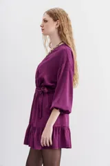 Vestido corto de estilo cruzado, color negro, con mangas largas abullonadas, puños elásticos y volado en el ruedo. Presenta un diseño de jacquard con corazones y cierre frontal con botones metálicos.