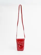 Porta celular tipo bandolera de cuero charol rojo, de diseño vertical con solapa decorada con tachas metálicas plateadas en forma de arco y correa larga fina.