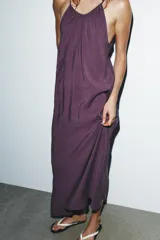 Vestido midi color lila de cuello halter y tirantes finos ajustables en la espalda.