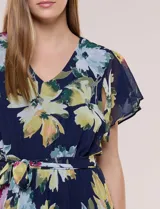 Vestido midi azul marino con estampado floral multicolor, confeccionado en gasa liviana con falda plisada. Tiene escote en V, mangas cortas estilo mariposa y lazo ajustable en la cintura.