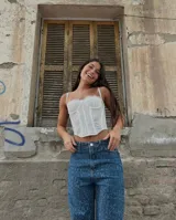 Corset blanco de encaje con tirantes finos y escote corazón, con varillas visibles para estructura.