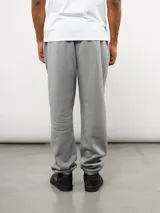 Pantalón de jogging de felpa con friza, color gris, con cintura elástica, bolsillos laterales y puños en los tobillos. Presenta un parche con el logo de Umbro en la parte superior delantera.