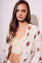 Blusa blanca con bordado de cachemir en negro, corte oversize y mangas acampanadas.