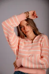 Buzo de punto color beige con rayas horizontales blancas, cuello polo con cierre de cremallera y mangas largas.