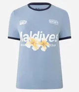 Remera ajustada de algodón color celeste claro con cuello redondo y ribetes en azul marino. Presenta un estampado frontal con la palabra "Maldivas" en blanco y un diseño floral en tonos amarillos y naranjas. Incluye pequeños logos bordados en blanco en el pecho.