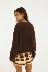 Cardigan básico de punto color marfil, con textura suave y esponjosa, cierre frontal de botones y mangas largas holgadas.