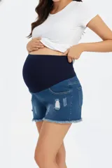 Short de jean de mezclilla azul con roturas y efecto gastado en el frente. Posee una faja de algodón elástica de color azul marino que cubre la zona del abdomen, ideal para maternidad. El ruedo es deshilachado.
