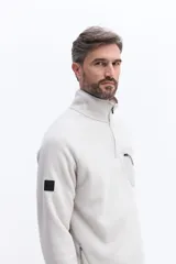 Buzo de polar color marrón con cuello alto y cierre frontal parcial. Presenta un bolsillo frontal con cierre en contraste de color y mangas largas.