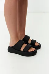 Sandalias planas negras con doble tira ancha.