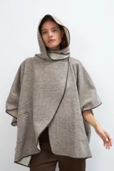 Ruana color crudo de lana fina sin teñir, con capucha, bolsillos y terminaciones envivadas. Tiene un broche para usar cerrada. Es una prenda oversize sin forro, cómoda, versátil y fácil de combinar.