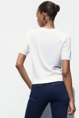 Jersey de punto fino con cuello redondo y manga corta, con terminaciones en rib en cuello, mangas y ruedo.