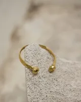 Brazalete rígido abierto de metal color plateado, con terminaciones en forma de herradura.