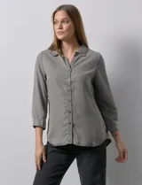 Camisa gris de tencel con cuello con solapa, escote en V y abertura central con botones. Largo de manga regulable con presilla y botón. Ruedo en espalda con tajo.