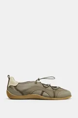 Zapato tipo bailarina deportiva color verde oliva con detalles en beige claro. Presenta cuerpo con contraste de materiales, sistema de ajuste elástico con tope fruncidor y suela de goma color caramelo.