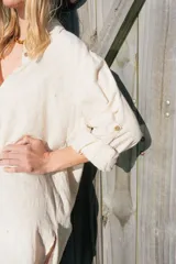 Túnica camisera de lino color beige, de corte largo y holgado, con mangas largas y bordado en la espalda con motivo de coral y texto.