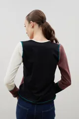 Remera de manga larga con diseño de bloques de color en tonos neutros, confeccionada con costuras externas visibles en color azul contrastante.