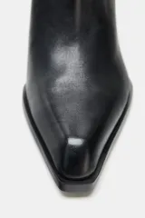Botín estilo cowboy de piel color negro, con caña baja, acabado en punta y tacón medio en bloque. Cuenta con cierre mediante cremallera lateral.