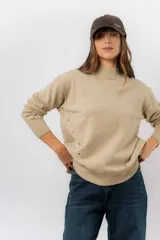 Sweater de tejido de punto color marrón, con cuello alto, corte relajado y terminaciones en rib en puños y cintura. Presenta una hilera de botones metálicos decorativos en uno de los laterales.