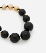 Collar maxi de esferas grandes de resina negra combinadas con pequeñas cuentas doradas.