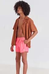 Short de baño color rosa neón, de corte clásico, con cintura elástica ajustable y cordón trenzado. Incluye dos bolsillos laterales, un bolsillo trasero con cierre y suspensor de malla fina estampado.