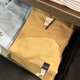 Camiseta de manga larga Guess color mostaza, con cuello polo y cierre frontal parcial. Presenta el logo de la marca bordado en el pecho.