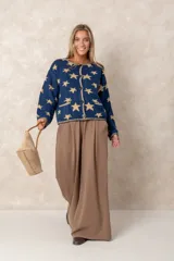Saco abotonado de punto con diseño de estrellas en contraste, cuello redondo, mangas largas y dos bolsillos frontales. Presenta bordes con terminación enrollada.