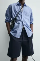 Bermuda de hombre color azul marino, de corte relajado (relaxed fit), confeccionada en tejido con textura. Presenta bolsillos frontales y bolsillos traseros de vivo, con cierre frontal de cremallera y botón.