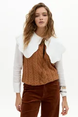 Chaleco de punto color caramelo con ochos en el frente, cuello a la base y terminaciones de rib.