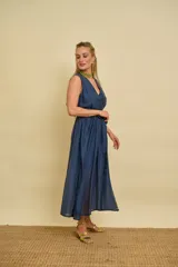 Vestido cruzado de organza color marrón, con escote en V, sin mangas y lazo para ajustar en la cintura. Presenta una falda con diseño asimétrico, más corta adelante y larga atrás.