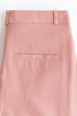 Pantalón de corte ajustado en sarga de mezcla de algodón y lino, color rosado. Modelo de tiro alto con cierre y botón, bolsillos insertados adelante y bolsillos decorativos atrás. Piernas acampanadas con raya adelante y atrás.