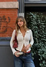Camisa de textura crinkle color blanco, con cuello camisero, escote en V profundo y cierre frontal con botones. Calce entallado al cuerpo y manga larga.