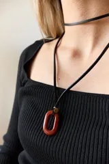 Collar con tiento negro y dije de piedra natural ovalada en tonos grises y azules.